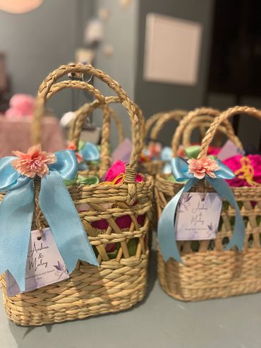 Woven gift baskets adorned with blue ribbons and flowers.