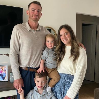 A happy family of four posing indoors with smiles.