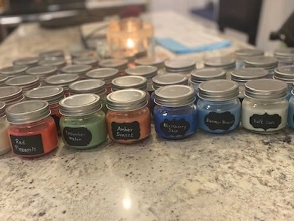 Rows of small colorful jars with labels on a marble countertop.