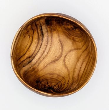 A round wooden bowl with natural grain patterns on a white background.