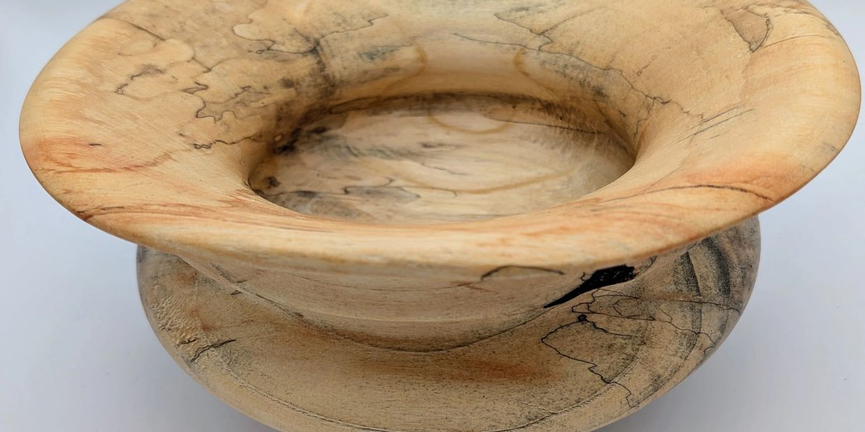 Handcrafted wooden bowl with natural grain patterns and a wide rim.