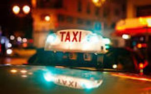 Close-up of a glowing taxi sign at night in a busy city.