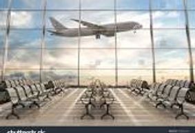 An airplane flying over an empty airport terminal seating area.