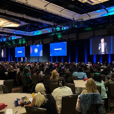 Large audience attending a professional conference with presentations on stage.