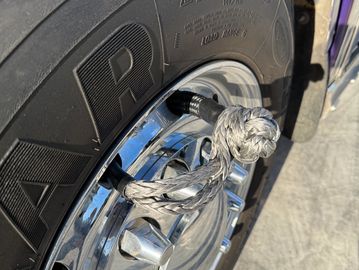 A knotted rope attached to a tire valve on a chrome wheel.