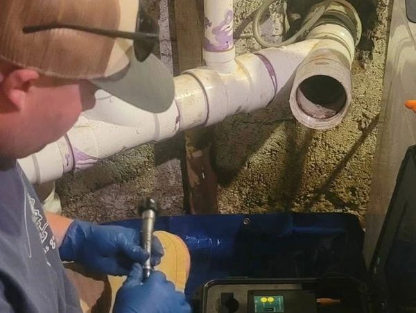 Worker fixing plumbing pipes in a basement.