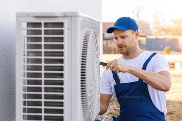A technician works on an outdoor AC unit.