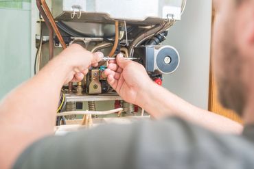 Hands work on the internal components of a furnace.
