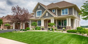 A photo of a suburban house with green grass.