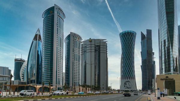 A skyline of modern skyscrapers and a wide road in the city of Doha, Qatar.