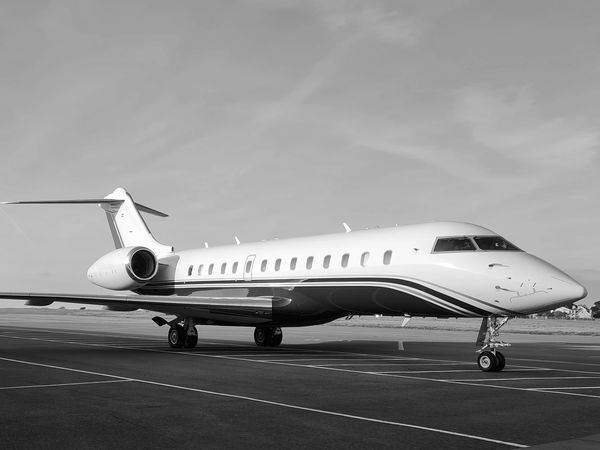 A sleek private jet parked on an airport runway under a clear sky.
