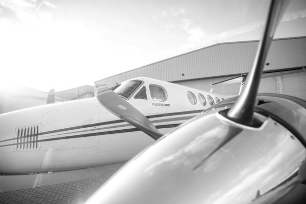 Black and white close-up of a small propeller airplane on the ground.