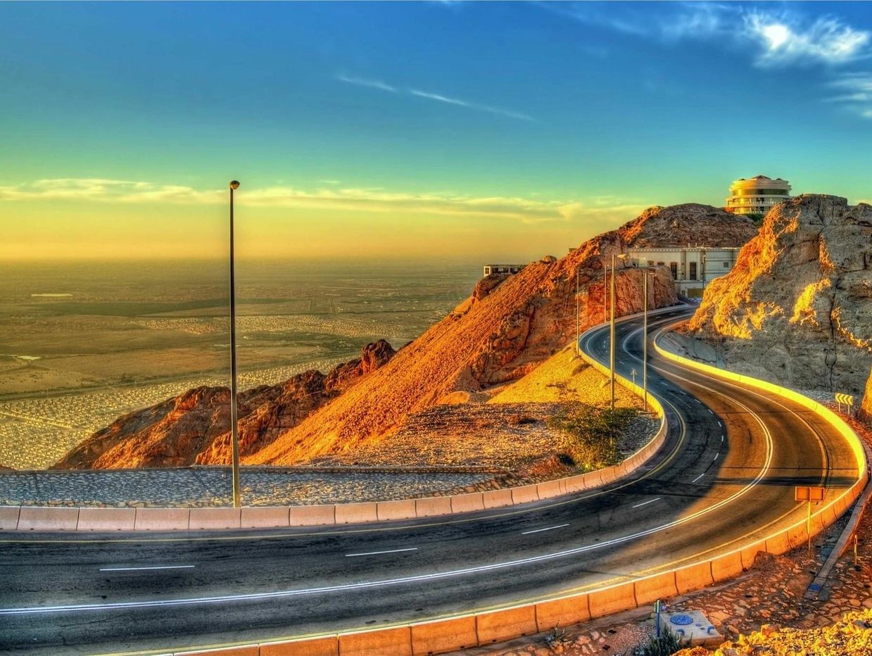 A winding mountain road illuminated by golden sunlight at sunset.