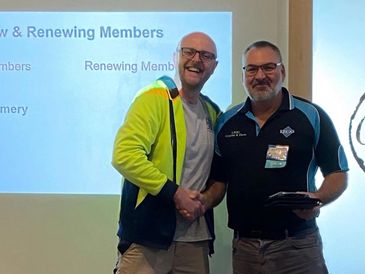 Two men shaking hands, smiling during a membership event.