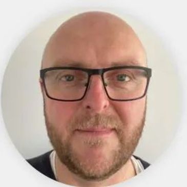 Smiling bald man wearing glasses.