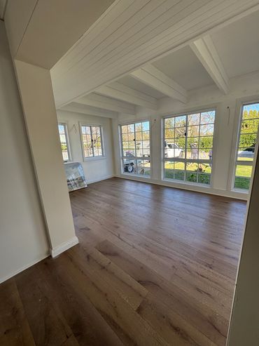 Bright empty room with wooden floor and large windows.