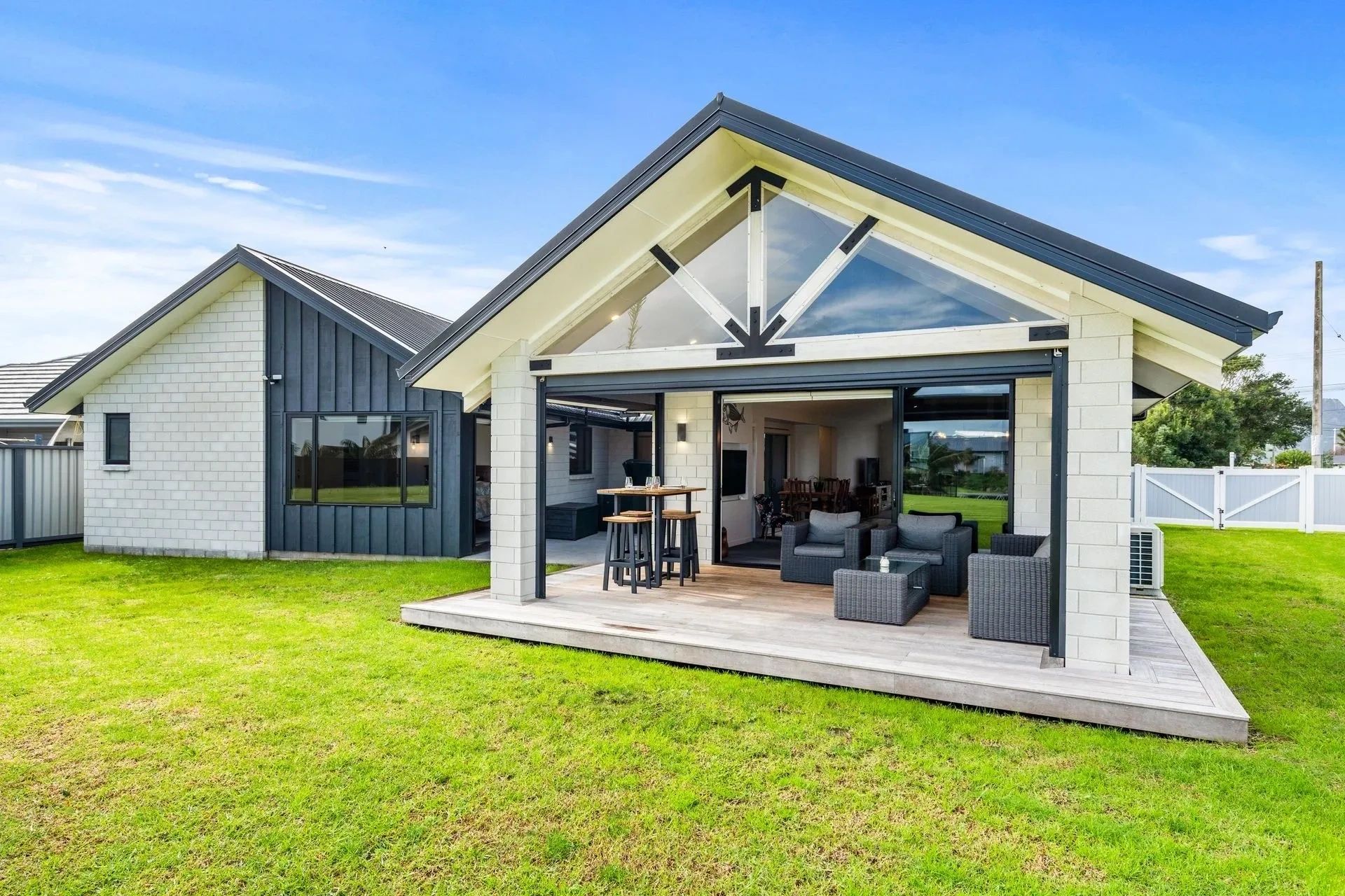 Modern house with outdoor seating and green lawn.