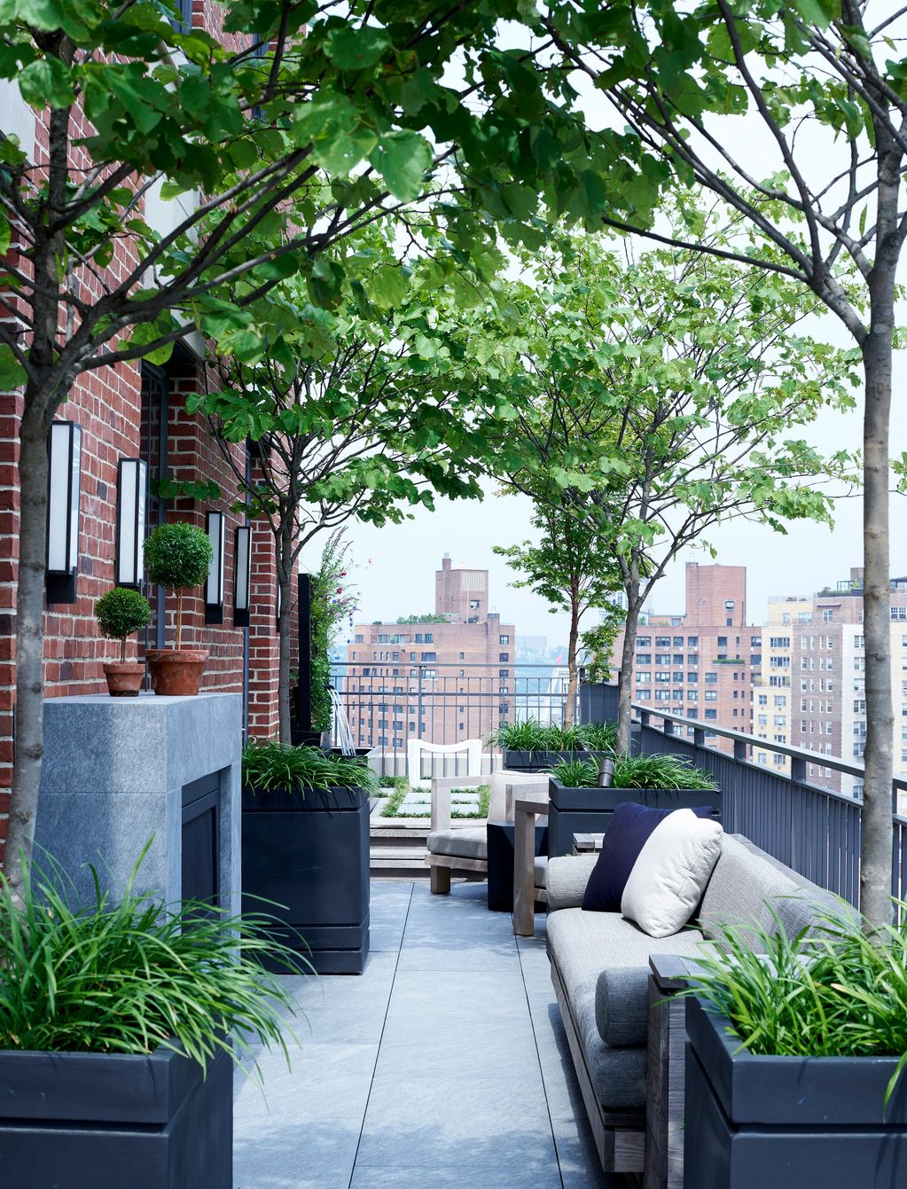 Modern rooftop terrace with greenery and cityscape views.