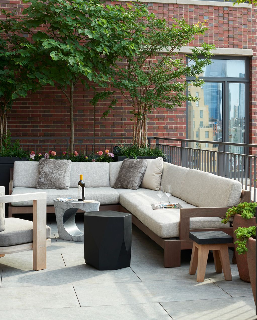 Modern outdoor seating area with a sectional sofa, plants, and a city view.