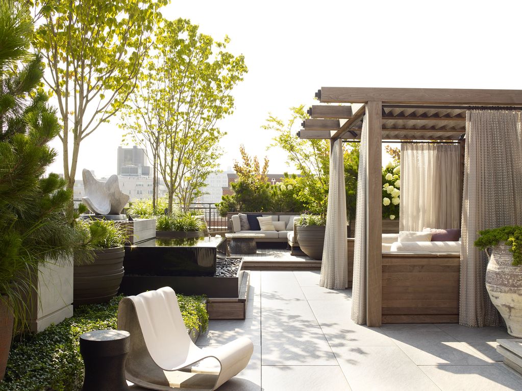 Modern rooftop garden with seating, greenery, and a shaded daybed area.