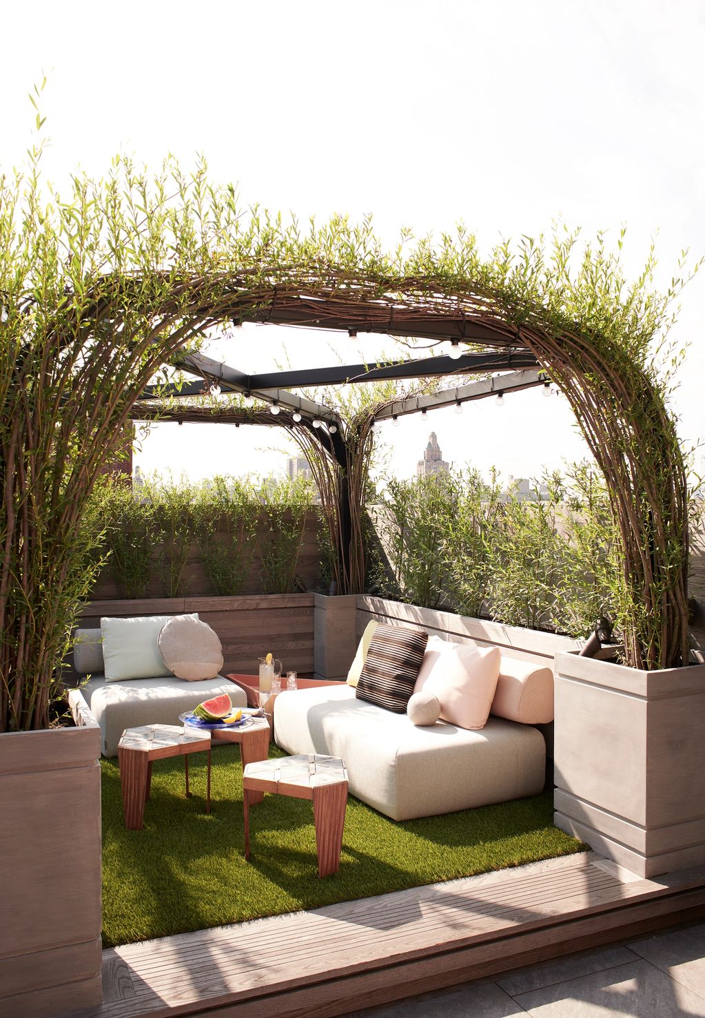 Cozy rooftop seating area with leafy arch and modern furniture.
