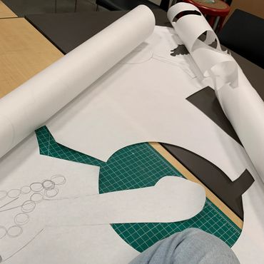 A large piece of paper begins to roll up. On the paper, large shapes are cut out of it.