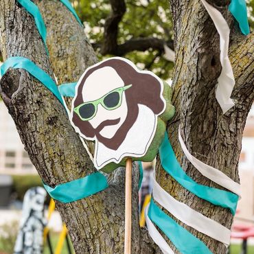 A totem of William Shakespeare leans up against a tree with light blue and pink streamers