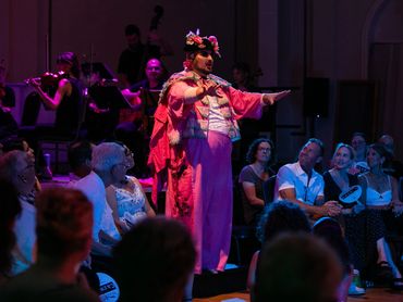 An actor dressed as a toreador stands on a step within the audience.