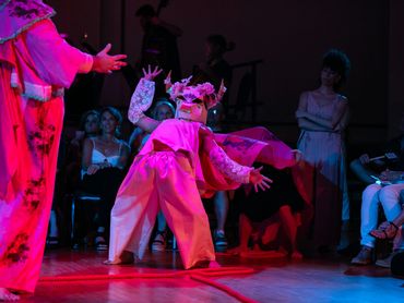 Two actors embody a bull costume, the one in front leans back in surprise.