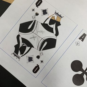 A piece of paper with a drawing of a Queen of Diamonds. It is more silhouette than detail.