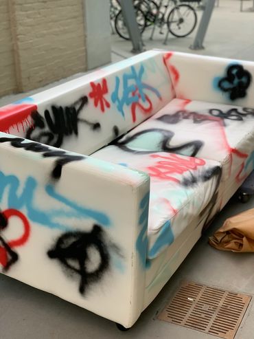 An off-white couch spray painted with red, light blue, and black.