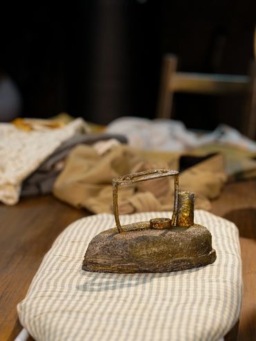 An image of an iron on a board, clothes lay behind it.