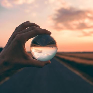 Image démontrant la perception que nous avons. Une main d'homme tient une sphère et le paysage qui s