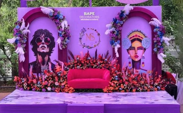 Vibrant purple event stage with artistic portraits and floral decorations.
