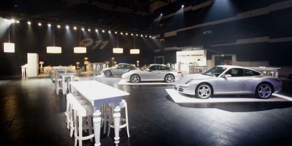 Three silver Porsche 911 cars displayed in a sleek showroom.