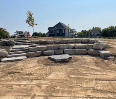 3 tier retaining wall with a landscape bed in the second layer. Natural steps, fire pit base