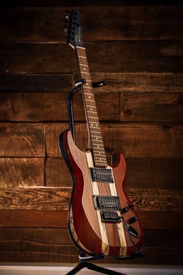 Electric guitar with a wooden striped body on a stand.