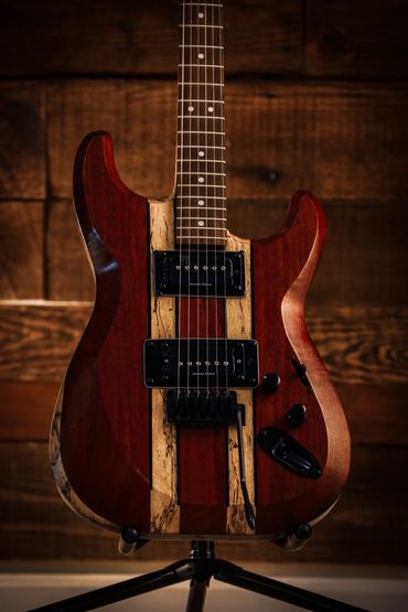 Close-up of a wooden electric guitar with dual pickups on a stand.