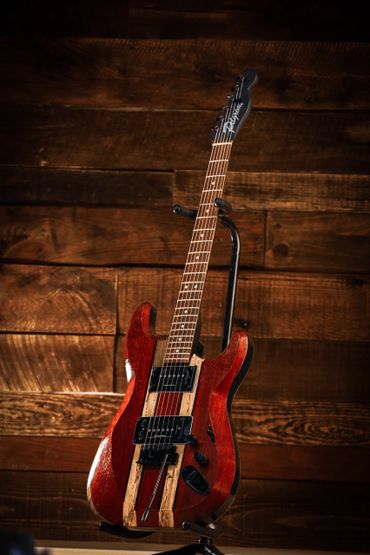A polished wooden electric guitar with dual pickups on a stand.