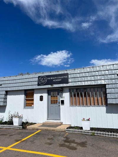 Building facade of The Beauty Collective Academy under a blue sky.