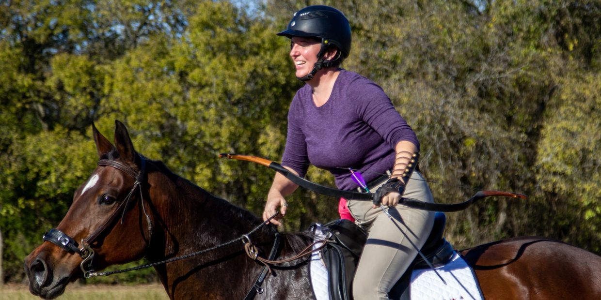 Coach Lindsay galloping on her horse Daisy with bow and arrow in hand