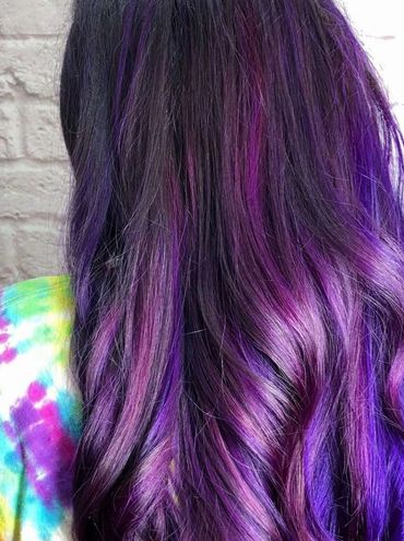 Long wavy hair dyed in vibrant shades of purple and violet.