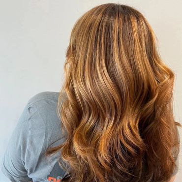 Back view of long, wavy, golden-brown hair with subtle highlights.
