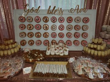 Donut wall rental with donuts decorated with white, pink and rose gold icing. 