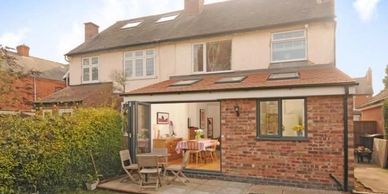 Two-story brick home with a modern ground floor extension and garden patio area.