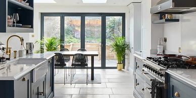 Modern kitchen with blue cabinets and large glass doors leading to a garden.