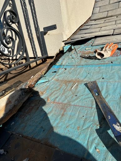 Roof repair in progress with tools and gloves on underlayment.