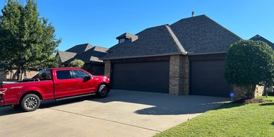 A red pickup truck parked in front of a modern house with a blue sky.