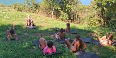 Children exercising outdoors on mats.
