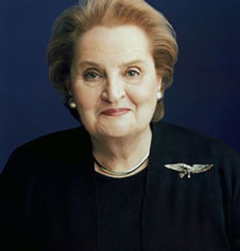Portrait of an elderly woman with a gentle smile, wearing a dark outfit and brooch.